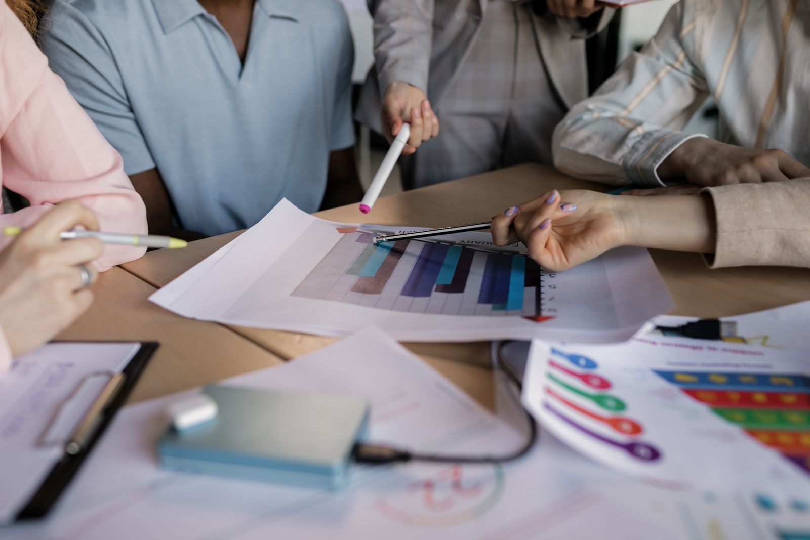 Team members pointing pens at printed marketing charts