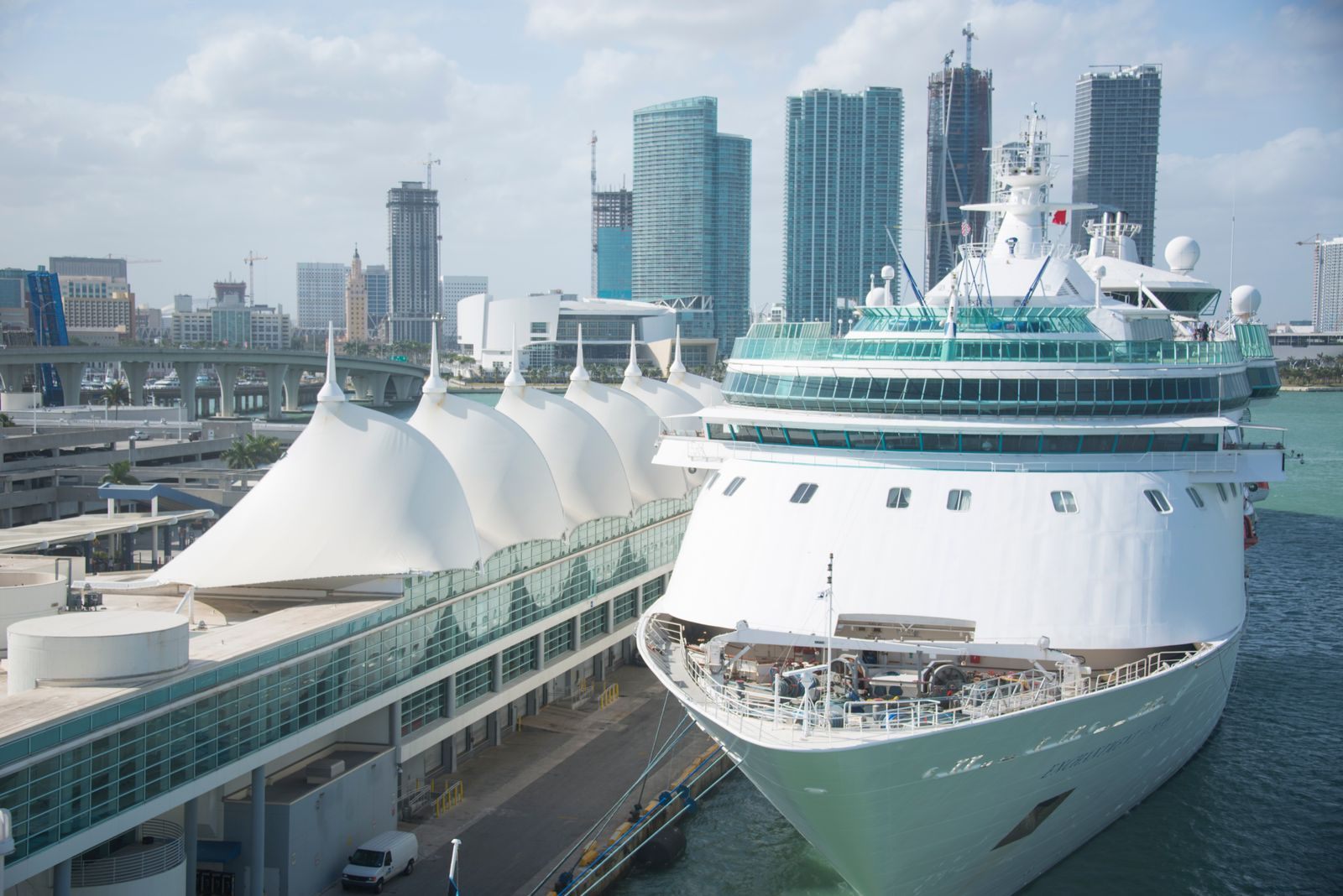 Cruise ship berthed at a sail-roofed cruise terminal in a city harbor