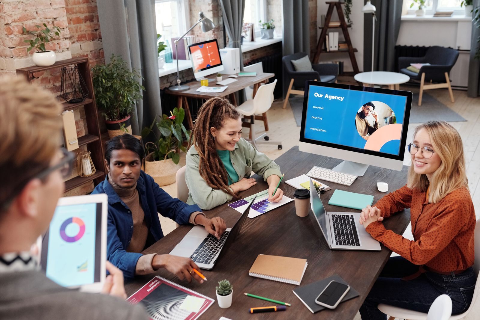 Marketing team working on laptops and a tablet around a shared desk
