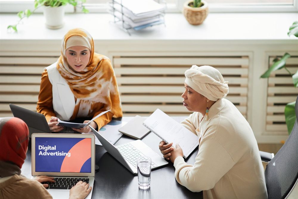 Two colleagues reviewing a digital advertising plan on laptops